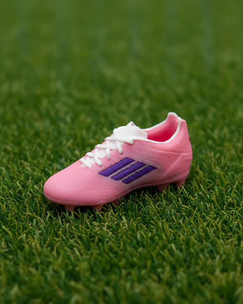 Small pink shoe with a white sole on a light wooden surface