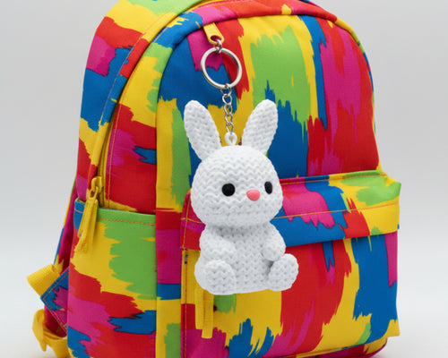 White crochet bunny toy with black eyes and a pink nose on a light gray background