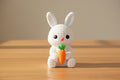 White crochet bunny with a carrot on a gray background