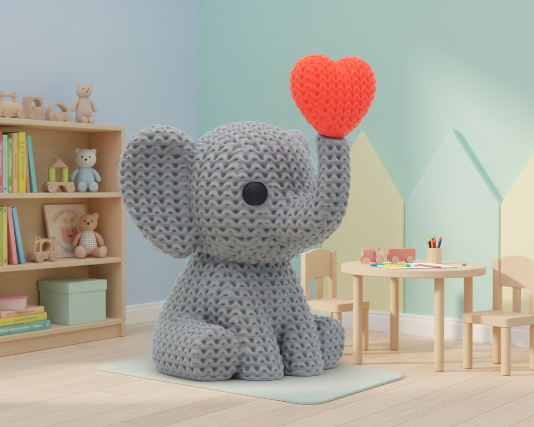 Gray crochet elephant holding a red heart on a white background