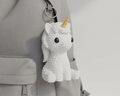White unicorn plush toy with a yellow horn on a pink background